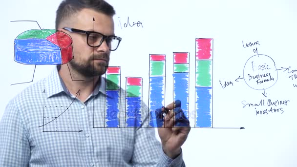 El hombre dibuja varias tablas de crecimiento, calculando las perspectivas de éxito en una moderna oficina de vidrio — Vídeos de Stock