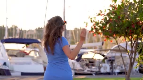 Femme en lunettes de soleil marchant le long du quai avec beaucoup de yachts et bateaux au coucher du soleil, fermer. Mouvement lent — Video