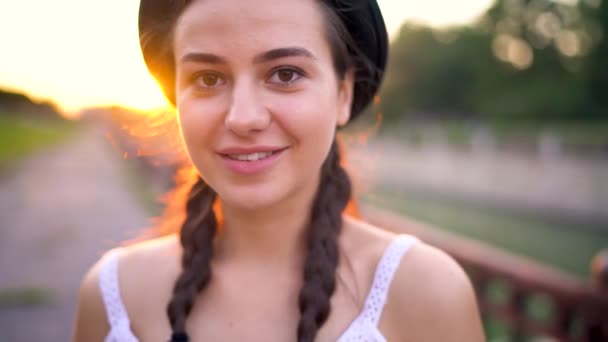 Портрет молодой улыбающейся девушки в шляпе на открытом воздухе — стоковое видео