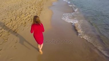 Üstten Görünüm ıslak kum plaj boyunca çıplak ayakla çalışan bir kadın. Kumun üzerinde çalışan dalga uzakta ayak yıkama