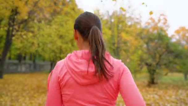 Close up of woman running through an autumn park at sunset — Stock Video