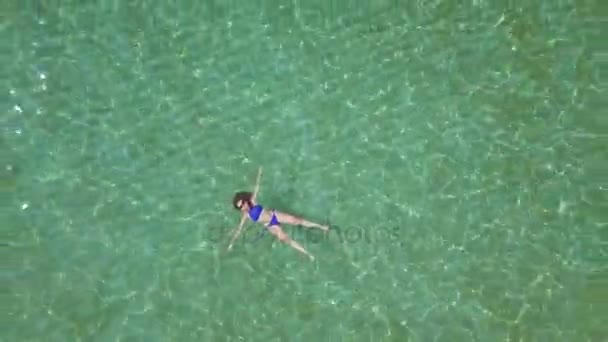 Розслаблена красива дівчина лежить на спині в літньому морі — стокове відео