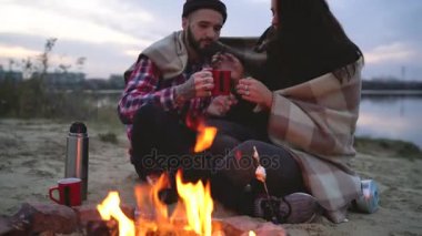 Şenlik ateşinde göl çevresinde oturan, söz ve içme aşık çift sıcak çay