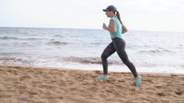 Plaj boyunca çalıştıran atletik kadın. Ağır çekim