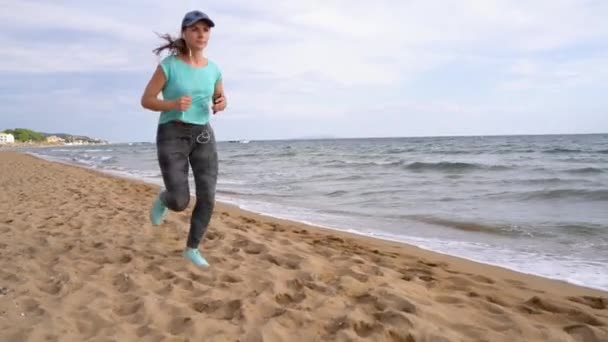 Athletische Frau, die am Strand entlang läuft. Zeitlupe — Stockvideo