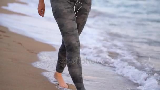 Donna atletica con cuffie passeggiando lungo la spiaggia — Video Stock