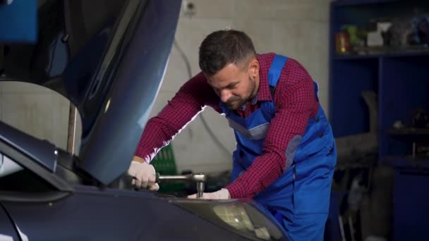 Servicio de coches, reparación, mantenimiento y concepto de personas - mecánico de automóviles trabajando en el taller — Vídeo de stock