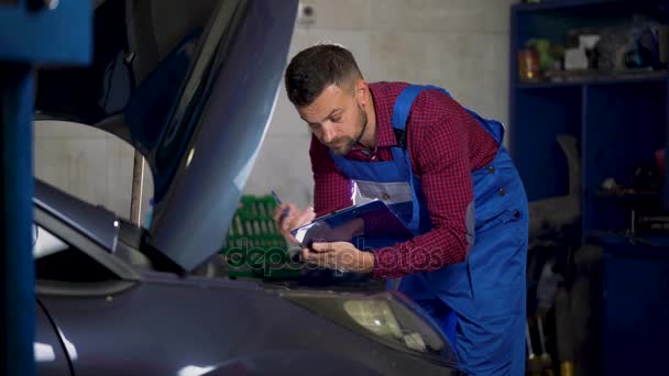 Servizio auto, riparazione, manutenzione e concetto di persone - il meccanico controlla la qualità del lavoro svolto — Video Stock