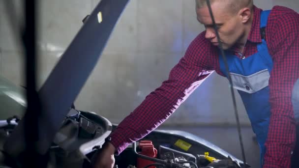 Service automobile, réparation, entretien et concept de personnes - mécanicien automobile travaillant à l'atelier 