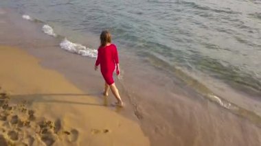 Üstten Görünüm yalınayak ıslak kum plaj boyunca yürüyen bir kadın. Kumun üzerinde çalışan dalga uzakta ayak yıkama