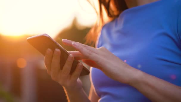 Vrouw in met behulp van een smartphone buitenshuis bij zonsondergang zonnebril — Stockvideo