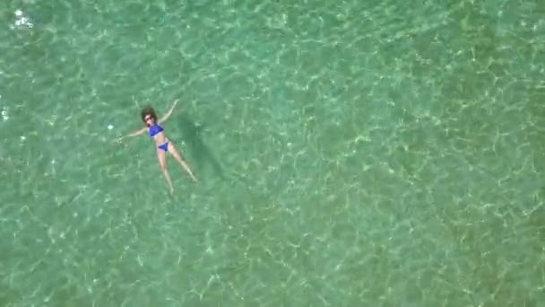 Розслаблена красива дівчина лежить на спині в літньому морі — стокове відео