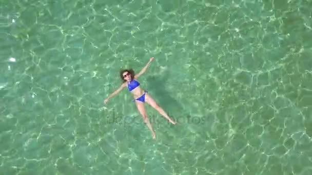Χαλαρή όμορφο κορίτσι βρίσκεται ανάσκελα στην θάλασσα και το καλοκαίρι — Αρχείο Βίντεο