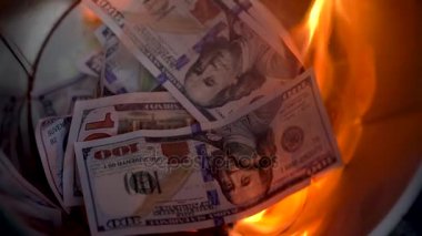 Çöp yakma dolar yakın çekim yapabilir ve bir adam yeni faturaları ateşe atar. Ağır çekim