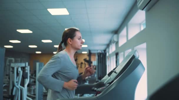 Mujer corriendo en la cinta en el gimnasio — Vídeo de stock