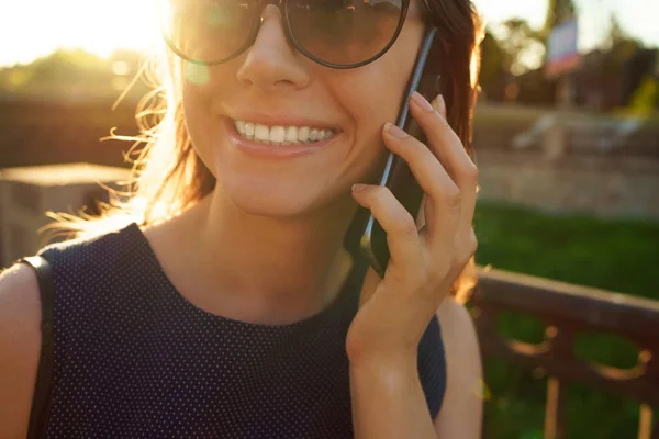 Mujer con gafas de sol hablando en el smartphone mientras camina —  Fotos de Stock
