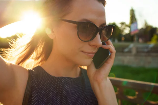 Frau mit Sonnenbrille spricht auf dem Smartphone, während sie nach unten geht — Stockfoto