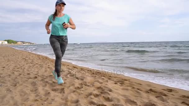 Спортивная женщина бегает по пляжу. Видео на разных скоростях - нормальное и медленное — стоковое видео