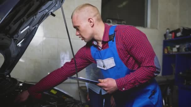 Bil service, reparation, underhåll och människor koncept - mekaniker kontrollerar kvaliteten på utfört arbete — Stockvideo