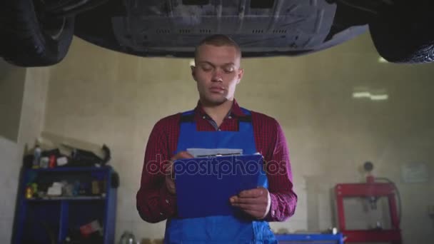 Serviço de carro, reparação, manutenção e conceito de pessoas - mecânico verifica a qualidade do trabalho realizado — Vídeo de Stock