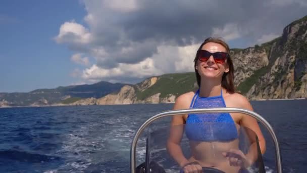 Vacaciones de verano - niña conduciendo un barco a motor en el mar — Vídeos de Stock