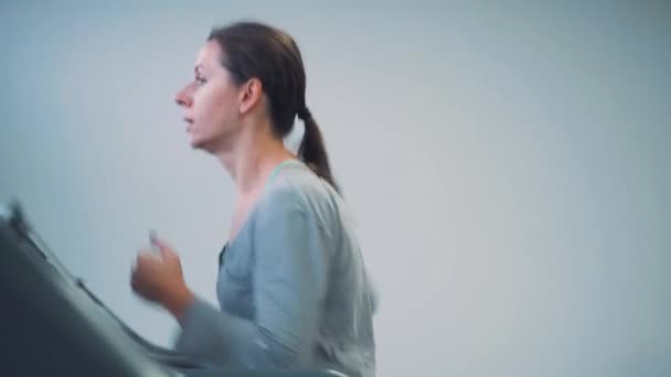Женщина бегает на беговой дорожке в спортзале — стоковое видео