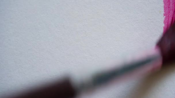 Desenho com um pincel sobre papel branco com aquarela vermelha de perto — Vídeo de Stock