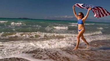 Bikini kadın bizimle bayrağı sahilde su çalışan plaj. Bağımsızlık günü ABD kavramı. Yavaş kavramı