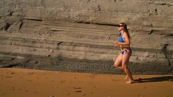 Plajă bikini femeie fără griji care rulează pe plaja de lângă stâncă. Coasta pitorească a mării din Corfu, Grecia. Slow motion — Videoclip de stoc