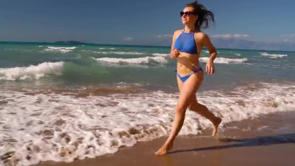 Bikini de playa mujer despreocupada corriendo por el agua en la playa. Pintoresca costa marítima de Corfú, Grecia. Concepción lenta — Vídeos de Stock