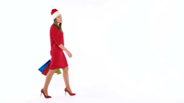 Karácsonyi női shopper gazdaság tarka bevásárló táskák, fehér háttér a stúdióban. Menjünk az üdülési bevásárló koncepció — Stock videók