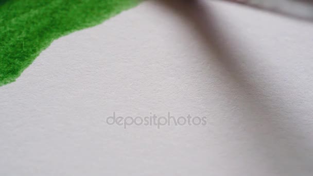 Drawing with a paintbrush on white paper with green watercolor close up — Stock Video