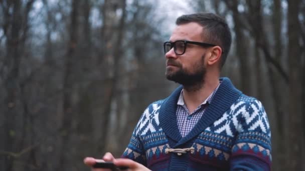 Homme à lunettes se promène dans la forêt d'automne et fait des photos par smartphone. Mouvement lent — Video