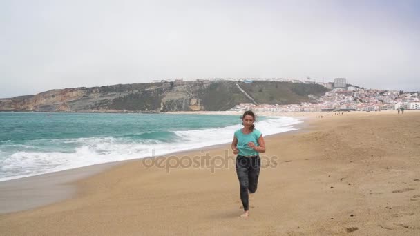 Athletic woman running along the beach — Stock Video
