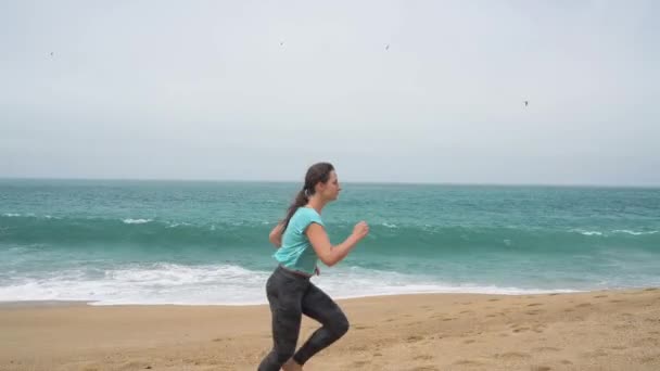 Kobieta lekkoatletycznego biegnącej wzdłuż plaży — Wideo stockowe