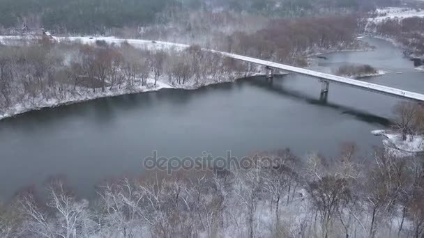 Vista desde la altura hasta el puente en el que los coches viajan sobre el río en invierno — Vídeo de stock