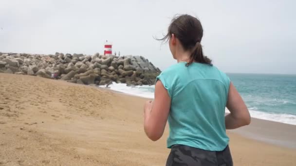 Mujer atlética corriendo por la playa. Movimiento lento — Vídeos de Stock