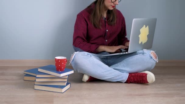 Красива дівчина використовує ноутбук і сидить на підлозі вдома — стокове відео