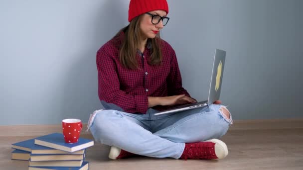 Hermosa chica usando el ordenador portátil y sentado en el suelo en casa — Vídeos de Stock