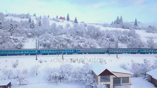 Вид с воздуха на поезд, проходящий через горную местность зимой — стоковое видео