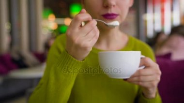 Bir kafede bir kaşık ile çırpılmış krema, çikolata şurubu ile kahve içme kadın