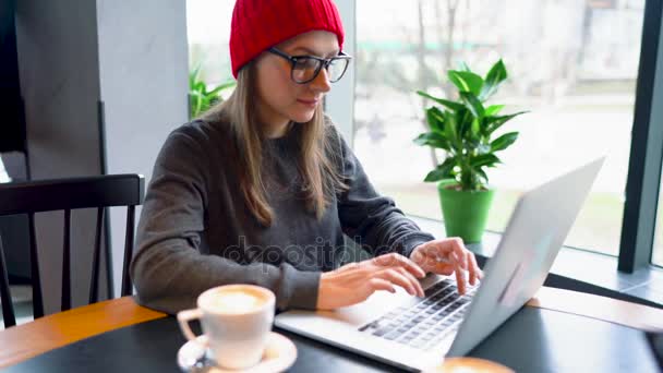 Mooie jonge vrouw werken en drinken koffie in een café — Stockvideo