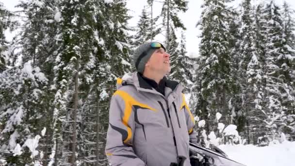 Человек с лыжами под мышкой поднимается к горе, готовясь к спуску — стоковое видео