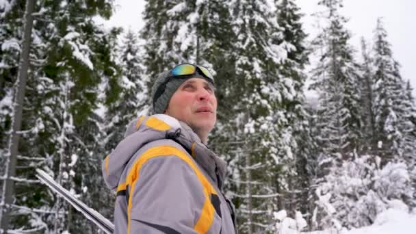 Mann mit Skiern unter dem Arm steigt auf den Berg und bereitet sich auf den Abstieg vor — Stockvideo