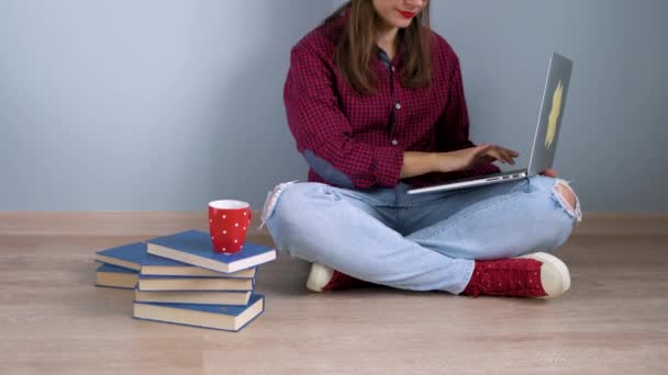 Девочка с помощью ноутбука и большого пальца сидит дома на полу — стоковое видео