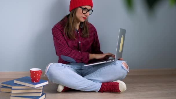 Mooi meisje met laptop zittend op de vloer thuis — Stockvideo