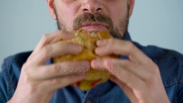 Человек ест сочный гамбургер — стоковое видео