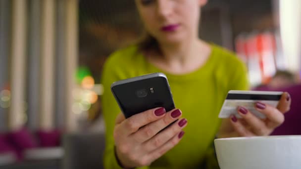 Frau nutzt Smartphone und Kreditkarte zum Online-Bezahlen im Café aus nächster Nähe — Stockvideo