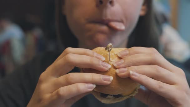 Mujer come una hamburguesa en un café — Vídeo de stock