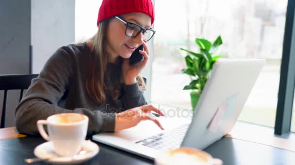 Bir kafede bir akıllı telefon konuşma ve çalışma güzel genç kadın — Stok video